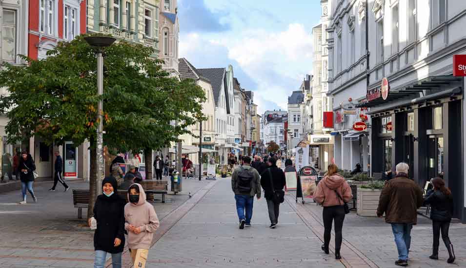 Blick auf eine Innenstadtstraße in Deutschland 2021 mit Passanten, manche tragen Masken.