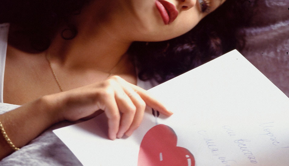 Eine Frau liest einen Liebesbrief mit einem roten Herz.