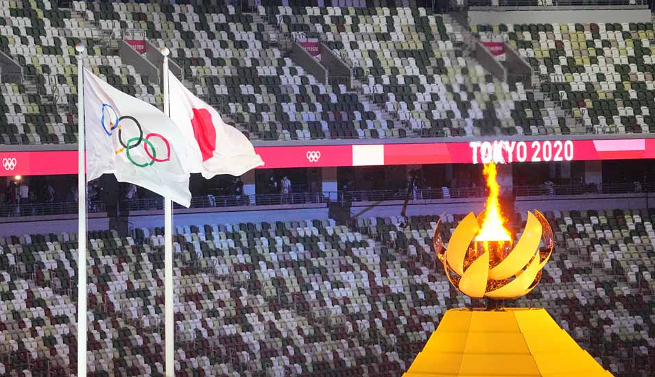 Olympia 2020/21: Eröffnungsfeier im Olympiastadion. Das Olympische Feuer brennt daneben die olympische und japanische Flagge. 