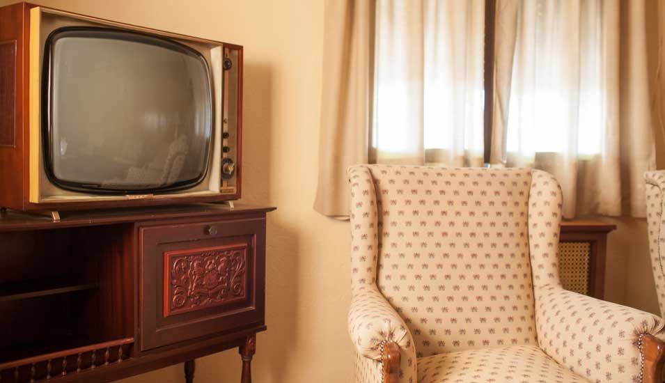 Ausschnitt eines Wohnzimmers im Retro-Look mit altem Fernseher und Polstersessel.