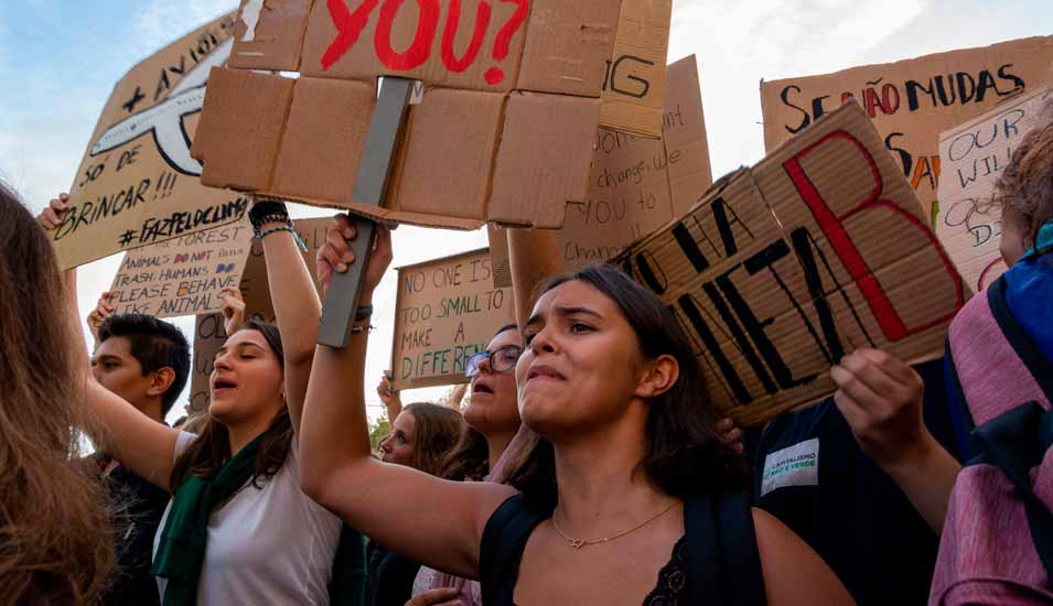 junge, wütende Demonstranten mit Protestschildern bei einem Klimastreik in Portugal