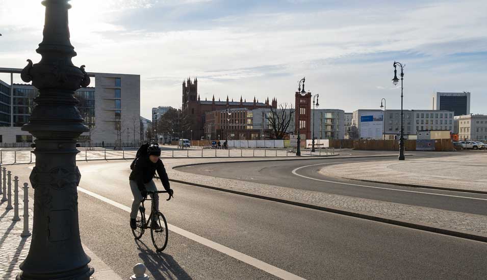 Blick auf eine leere Straße in Berlin Mitte, auf der nur ein Radfahrer zu sehen ist.