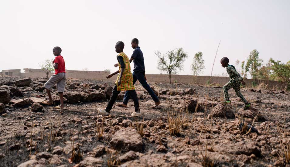 Afrikanische Kinder überqueren ein ausgedorrtes Feld in der Sahelregion
