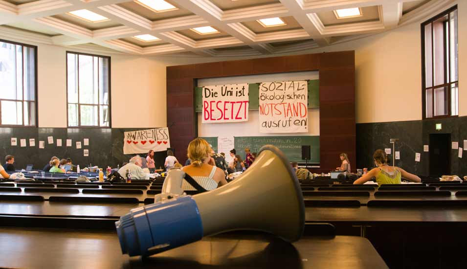 Mehrere Personen und Plakate in einem von Klimaaktivisten besetzten Hörsaal der Uni Freiburg