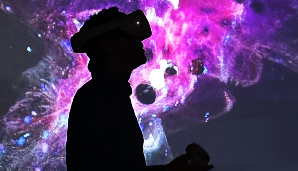 In einem dunklen Raum mit lila anmutenden Lichtwolken sieht man die Silhouette einer Person mit Virtual-Reality-Brille. 